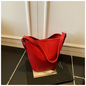 Detail of red crocodile embossed leather bucket bag texture and silver metal buckle