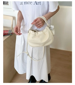 Detail of off-white ruched cloud bag with woven handle, pearl charms and shoulder strap