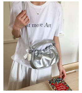 Silver pleated cloud bag detail with woven handle, lace bow, and pearl heart pendant