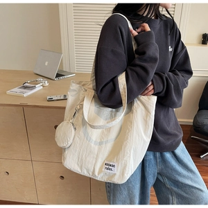 Detail of off-white tote bag with textured nylon fabric and a small round coin purse
