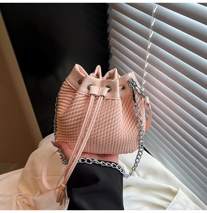 Detail of pink woven bucket bag with drawstring closure and silver chain strap