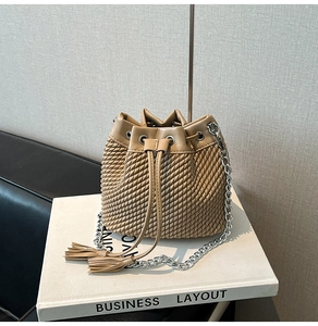 Detail of woven texture bucket bag with tassel drawstring and silver chain strap