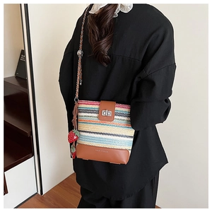 Detail of colorful striped straw bucket bag featuring silver twist lock and strawberry charm