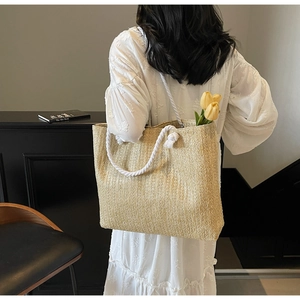 Detail of woven straw tote bag with white cotton rope handles and beige texture