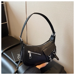 Detailed view of black litchi grain leather texture and silver biker hardware on hobo bag
