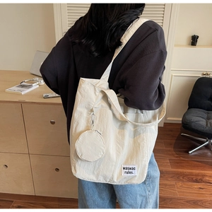 Detail of beige canvas tote bag with textured fabric and small circular zipper pouch