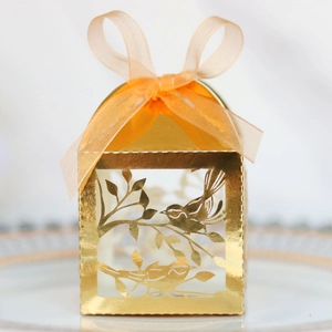 Detail of laser-cut golden bird wedding candy box with elegant translucent ribbon bow