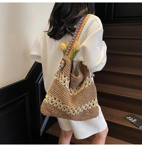 Detail of hand-woven straw shoulder bag featuring colorful geometric strap and hollow pattern