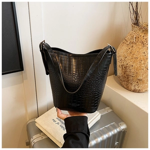 Detail of black crocodile texture bucket bag on luggage with a stylish commuting look