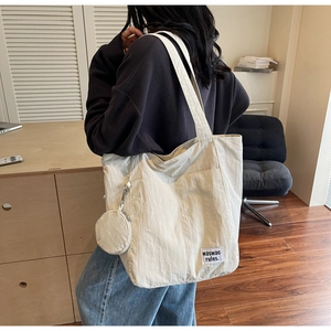 Detail of off-white canvas tote bag with small detachable zipper pouch and text print