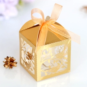 Macro detail of golden laser-cut wedding favor box with bird motif and ribbon