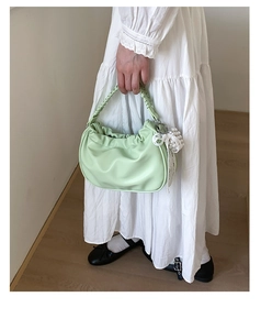 Detail of pistachio green pleated dumpling bag with woven handle and pearl lace charm