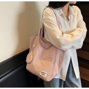 Detail of light pink tote bag with brand label and matching round coin purse pendant