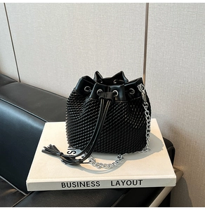 Detail view of black drawstring bucket bag with textured weave and silver chain strap