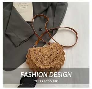 Detail of woven straw saddle bag with scalloped edges and brown leather shoulder strap