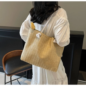 Detail of woven straw tote bag featuring thick rope handles and vertical knit texture