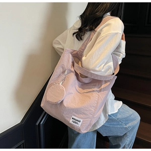 Lilac canvas tote bag with round coin purse shown from the side on a model