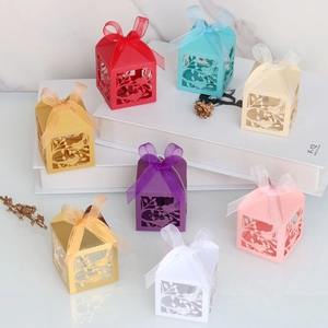 Detail view of multi-color laser-cut wedding favor boxes with bird patterns and ribbons