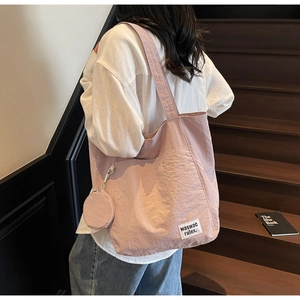 Detail of light pink tote bag with round coin purse and woven waswac rules label
