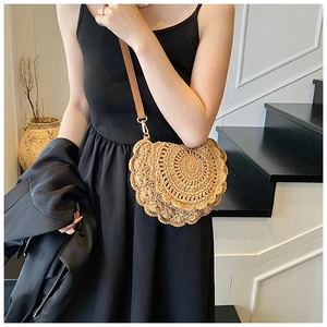 Detail of woven straw saddle bag with brown leather strap and gold metal hardware