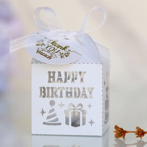 Detail of white laser-cut Happy Birthday candy box with ribbon and thank you tag