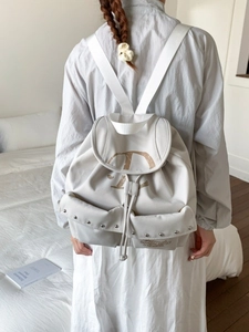 Sac à dos en toile beige minimaliste avec imprimé D et détails de rivets sur modèle
