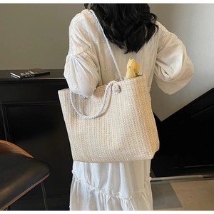 Detail of beige straw tote bag with white cotton rope handles and summer vacation style