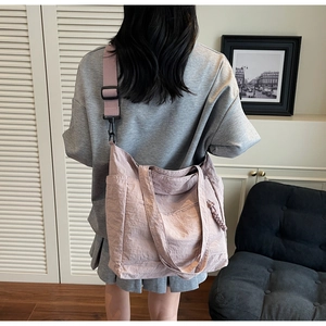 Detail view of large mauve nylon tote bag with pleated texture on female model's back