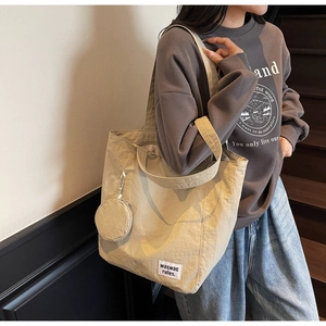 Close-up of beige minimalist canvas tote bag with a woven brand label and mini pouch