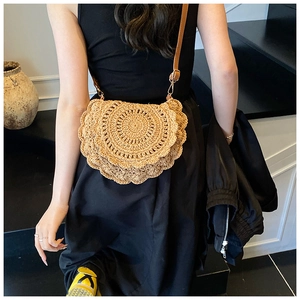 Detail of hand-woven straw saddle bag with wavy edges and adjustable leather strap