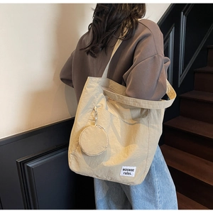 Detail of beige tote bag with nylon texture and small round matching coin purse accessory