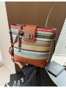 Colorful woven straw bucket bag with strawberry charms and a metal chain strap