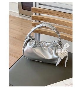 Detail of silver pleated cloud bag with woven handle and pearl heart lace charm