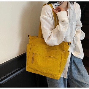 Detail of a bright yellow tote bag showing nylon texture and functional side pockets