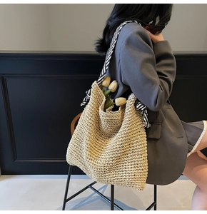 Detailed weave texture of straw tote bag featuring a black and white striped scarf handle