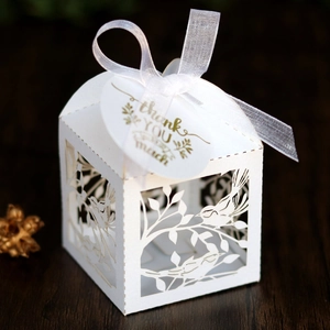 Laser-cut white wedding favor box with lovebird detail and 'Thank You' tag on wood