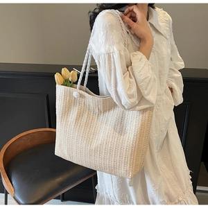 Detail of a beige straw tote bag with wave texture and large capacity for summer
