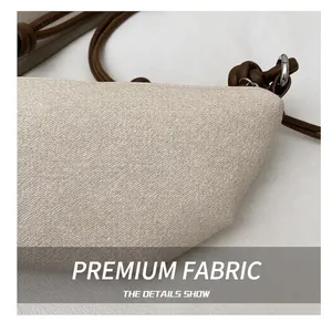 Détail du tissu beige tissé et de la bandoulière marron avec crochet métallique argenté