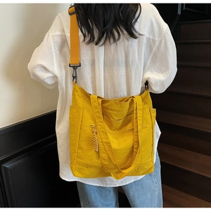 Detail of yellow canvas tote bag featuring side pockets and adjustable shoulder strap