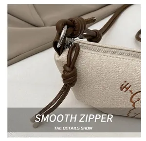 Détail de la fermeture éclair argentée et de la bandoulière en cuir du sac en toile