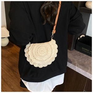 Detail of a beige round crochet bag with scallop edges and slim brown leather strap