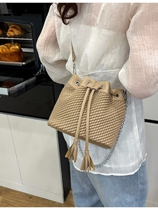Fashionable woven bucket bag in beige with tassel drawstring and silver chain strap