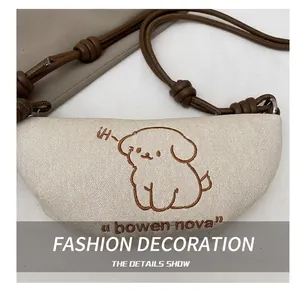 Gros plan sur la broderie de chien du sac demi-lune en toile avec bandoulière en cuir
