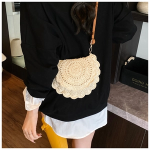 Detailed close-up of beige crochet saddle bag with scalloped edges and leather strap
