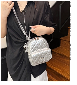 Close-up of silver quilted mini backpack with metallic finish and metal chain straps