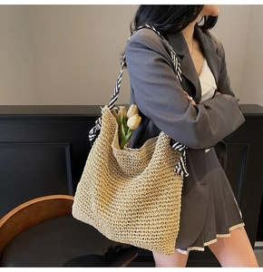Detail of hand-woven straw tote bag with black and white striped scarf on the handle
