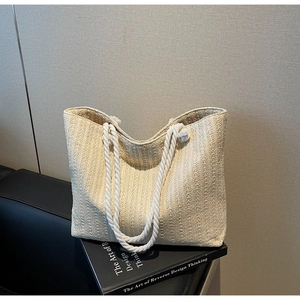 Detail of cream woven tote bag with thick cotton rope handles on a design book