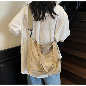 Side view of a large khaki nylon tote bag with pleated texture on a model on stairs