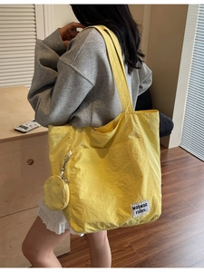 Large yellow canvas tote bag with round coin purse and white woven label on shoulder
