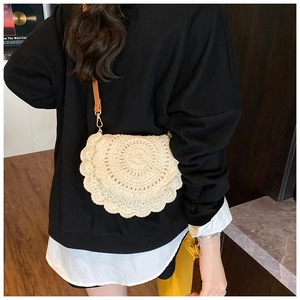 Detail of crochet knit saddle bag with wavy scalloped edges and brown leather strap